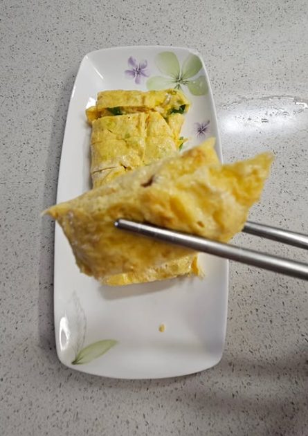 젓가락으로 집은 두툼한 계란말이 단면